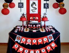 a table topped with lots of desserts and red paper lanterns hanging from the ceiling