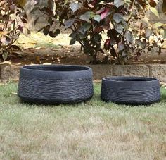 two planters sitting in the grass next to each other