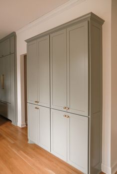 an empty room with white cabinets and wood floors