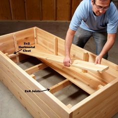 a man is working on the bottom part of a bed frame with wood planks