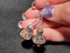 Introducing our stunning handmade lampwork frit bead earrings - the perfect accessory to add a touch of unique charm to any outfit! Each pair of trendy drop earrings is handmade using a blowtorch and first quality borosilicate glass, with a careful mix of colors and torch flames used to bring out the beauty in every bead. But the magic doesn't stop there - we love to add a little extra sparkle with crystals and sterling silver beads, creating a stunning movement in each dangle earring. At 2" lon Handmade Iridescent Round Bead Earrings, Handmade Iridescent Earrings With Round Beads, Iridescent Czech Glass Dangle Earrings, Handmade Czech Glass Earrings For Party, Handmade Silver Beaded Glass Earrings, Handmade Glass Crystal Drop Earrings, Handmade Iridescent Czech Glass Earrings, Silver Dangling Beads Glass Earrings, Handmade Glass Crystal Earrings For Gift