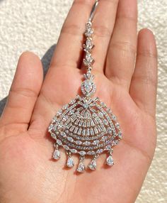 a hand holding a diamond necklace in it's left palm, with white background