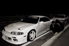 two white cars parked next to each other on the side of a road at night