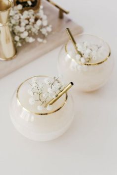 two white vases with flowers in them sitting on a table next to a tray