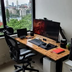 a desk with a monitor, keyboard and mouse on it in front of a window