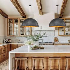 a large kitchen with wooden cabinets and white counter tops, two pendant lights over the island