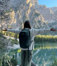 a woman with her arms outstretched in front of a mountain lake