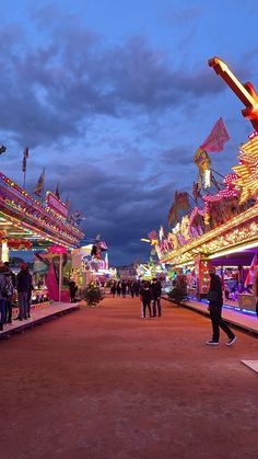 people are walking around an amusement park at night with lights and rides on the carousels