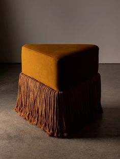 an orange ottoman with fringes on it