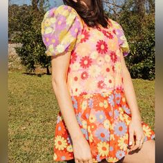 a young woman sitting in the grass with her hand on her hip