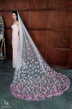 a woman standing in front of a wooden wall wearing a veil with flowers on it