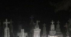 a cemetery at night with many headstones and crosses