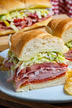 two sub sandwiches on a plate with chips