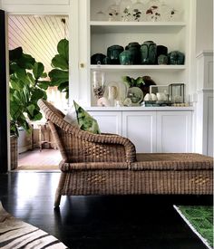 a wicker chaise lounge with green vases on the shelves in front of it