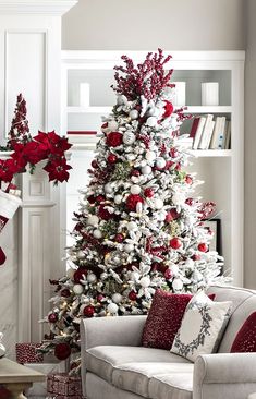 a living room decorated for christmas with red and white decorations on the tree, fireplace mantels and couches