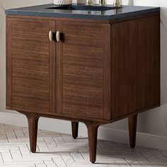 a wooden cabinet with black counter top and two brass faucets on the legs