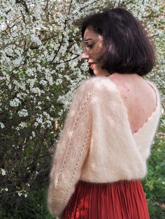 a woman standing in front of a tree with white flowers