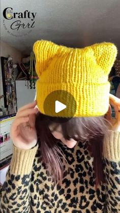 a woman wearing a yellow knitted cat hat with her hands on her head and the caption crafty girl