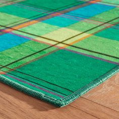 a green and blue plaid rug sitting on top of a wooden floor