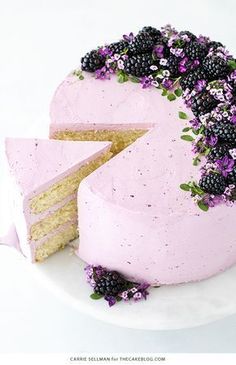 a cake with purple frosting and blackberries on the top is cut into pieces