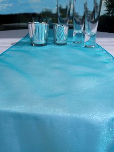 the table cloth is blue and has three glasses on it