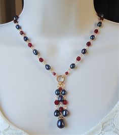 "You really can't go wrong with this classic necklace. It is so elegant and versatile, perfect for all seasons. This lariat style necklace combines luminous baroque black pearl with red garnet crystals. It features a decorative infinity circle plated in 24 karat gold. This necklace measures 16\" in length, with 2 inches extension. The pendant-tassel measures 2\" in length. This stunning necklace is unique, feminine and eye-catching, Perfect for anyone that wants to make a statement or to wear to Elegant Red Lariat Necklaces, Elegant Red Lariat Necklace, Elegant Beaded Dangle Necklaces With Lobster Clasp, Elegant Beaded Dangle Necklace With Lobster Clasp, Elegant Wire Wrapped Dangle Beaded Necklaces, Elegant Red Wire Wrapped Necklace, Ruby Choker, Lariat Style Necklace, Choker Handmade