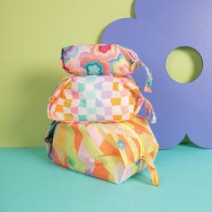 three colorful pillows stacked on top of each other in front of a purple and blue wall