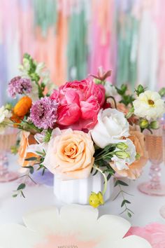 a white vase filled with lots of flowers on top of a table next to plates