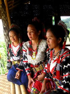 three women in native clothing sitting on a bench