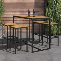 a table and four stools in front of a wooden wall with plants on it