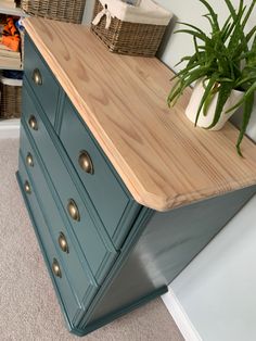 a green dresser with drawers and a potted plant sitting on it's top