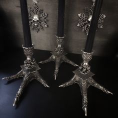 three silver candlesticks sitting next to each other on a black surface with snowflakes in the background