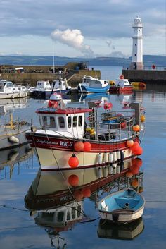 several boats are docked in the water near a lighthouse