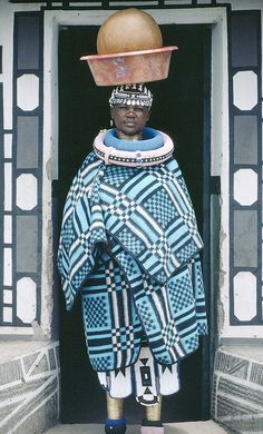 an african man wearing a blue and white outfit with a wooden hat on his head