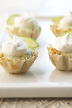 small cupcakes topped with whipped cream and lime slices on a white platter