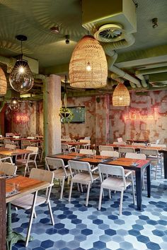 an empty restaurant with blue and white flooring, chandeliers and wooden tables