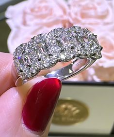 a woman's hand holding a diamond ring in front of a pink rose bouquet