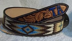 two belts are sitting next to each other on a white surface, one has a blue and brown design on it