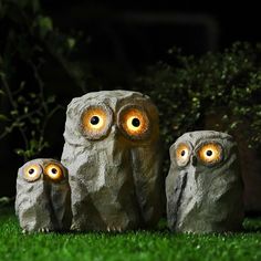 three owls with glowing eyes sitting in the grass