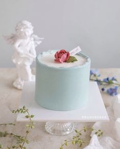 a blue cake sitting on top of a white plate next to a small figurine