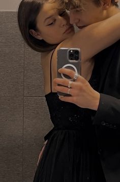 a man and woman taking a selfie in front of a mirror with their cell phone