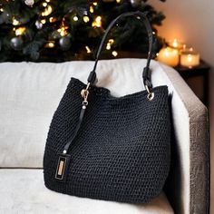 a black purse sitting on top of a couch next to a christmas tree with lights