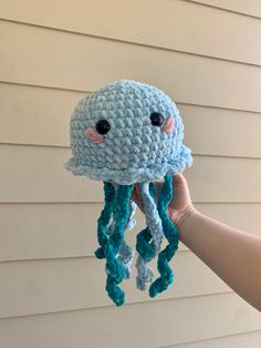 a hand holding up a crocheted jellyfish