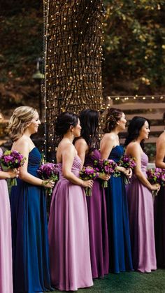 a group of women standing next to each other in long purple and blue gowns