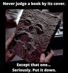 someone is holding up a book that looks like it has been carved into the ground