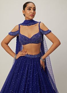 This stunning Blue Crystal and Sequin Embroidered Tulle Lehenga Set is a perfect blend of elegance and glamour. Crafted from soft net and georgette fabrics, the blue lehenga is intricately hand-embroidered and adorned with shimmering sequins that catch the light beautifully with every movement. Teamed with a jewelled blouse embellished with crystal detailing, it adds a touch of sparkle and sophistication, while the cold-shoulder design brings a modern twist to traditional wear. Completed with a matching dupatta, this lehenga set exudes grace. The off shoulder tassels can be added at an additional cost of GBP 45. Ideal for Sangeet, cocktail parties, or evening events. Composition : Lehenga, Dupatta - Soft Net and Blouse - Georgette Care: Dry Clean Only and Vacuum Storage This product can be Blue Embellished Georgette Lehenga, Party Choli With Resham Embroidery In Royal Blue, Blue Semi-stitched Embellished Lehenga, Semi-stitched Embellished Blue Lehenga, Blue Embellished Organza Lehenga, Blue Georgette Party Gown, Blue Embellished Organza Anarkali Set, Royal Blue Lehenga With Zari Work For Parties, Blue Organza Choli With Sheer Dupatta