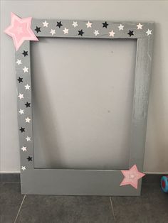 a gray frame with pink and white stars on the side, next to a blue toy