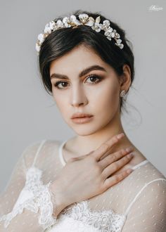 a woman wearing a tiara with flowers on her head and hands in front of her face