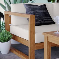 a white couch sitting on top of a wooden table next to a potted plant