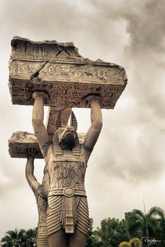 an ancient statue holding a large stone object